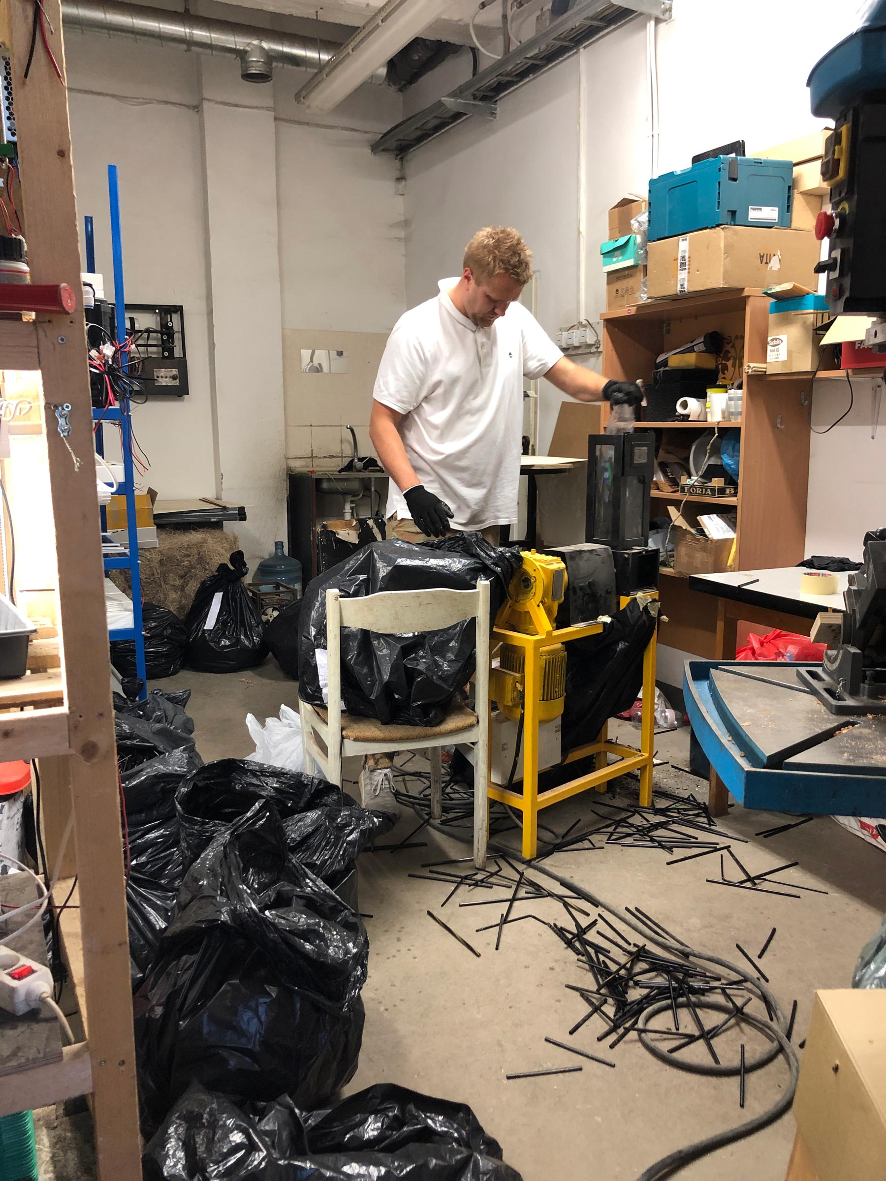 Shredding used plastic straws in a local technical hub to prepare materials for creating sustainable straw art sculptures.