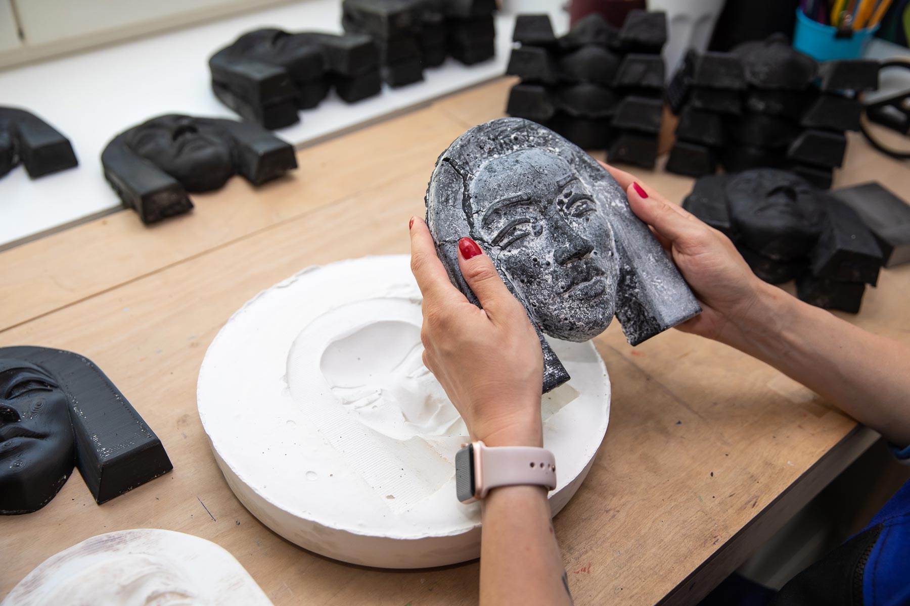 Artist removing a plastic straw sculpture from a gypsum mold during the creative process of transforming discarded straws into sustainable art.