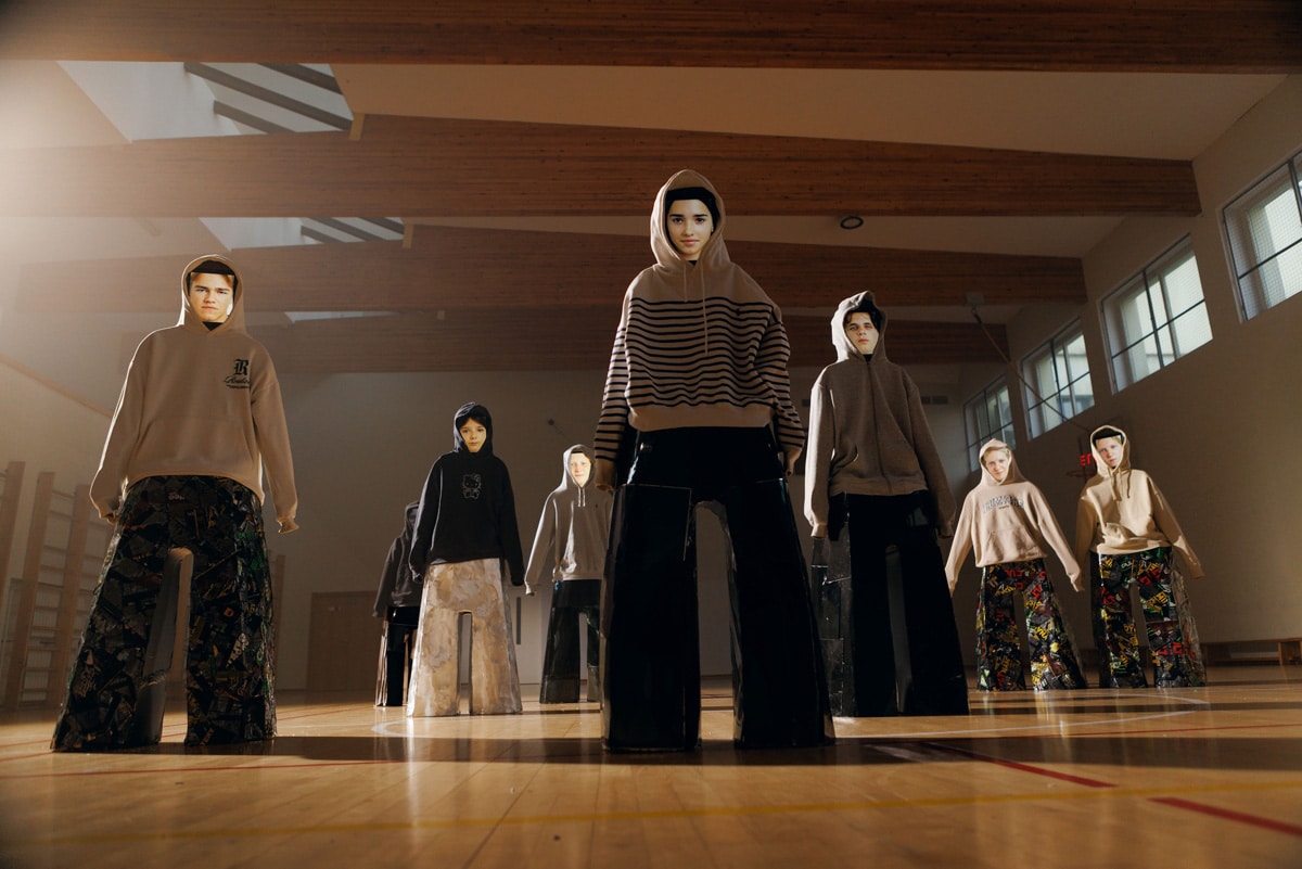 Front view of hooded figures from the Adolescence art installation by Agne Kisonaite displayed in a school gym