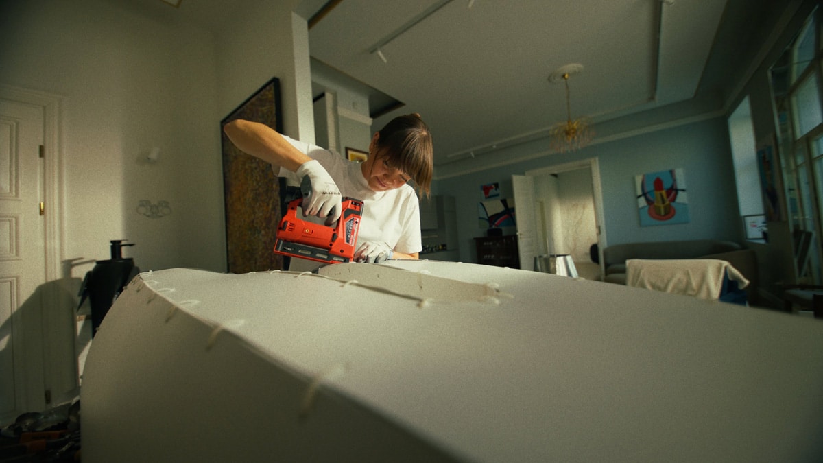 Agne Kisonaite assembling part of the Adolescence art installation structure in her studio using a power tool