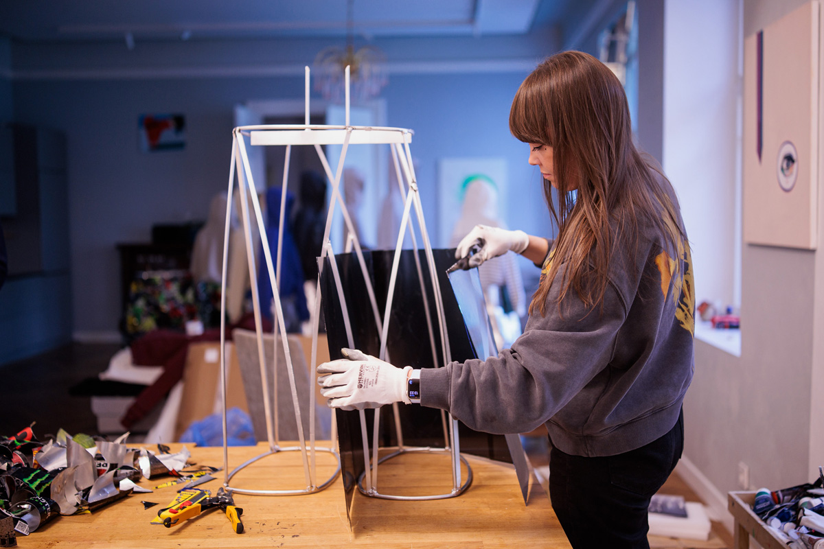 Agne Kisonaite attaching metal panels to a steel frame while constructing a figure for the Adolescence art installation.